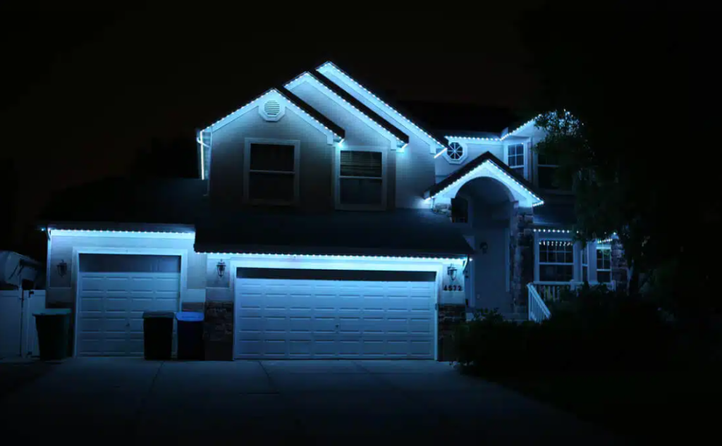 Permanent lighting on the outside of a two story house with a garage and driveway