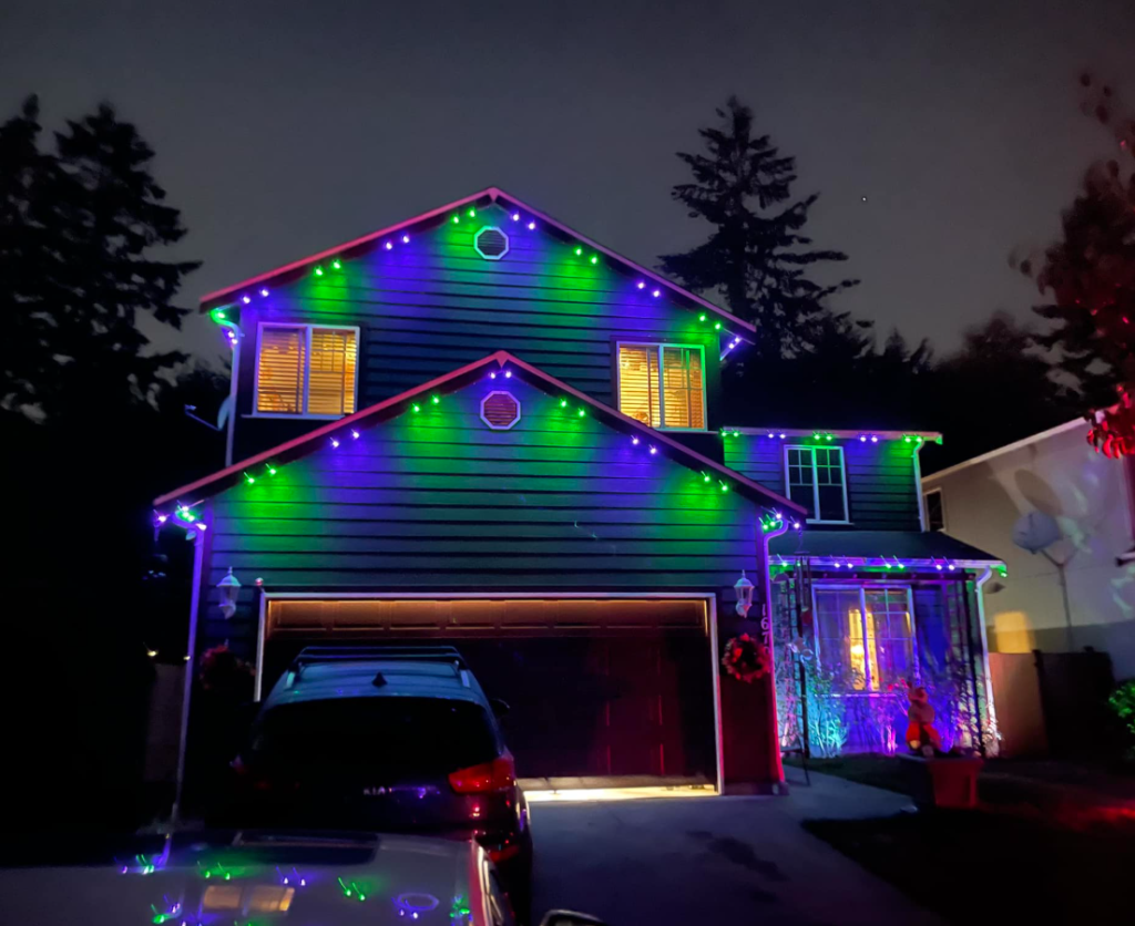 green and blue permanent lighting on the outside of a two story home with a car out front