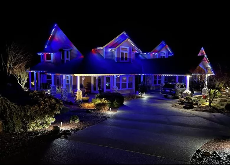 a two-story home with exterior lighting and a car parked out front