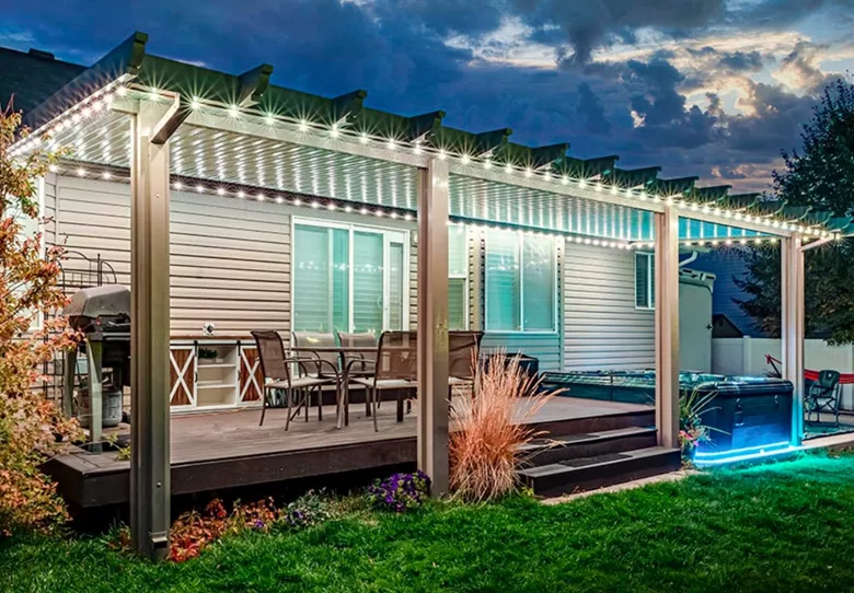 A backyard patio set up with exterior lighting 